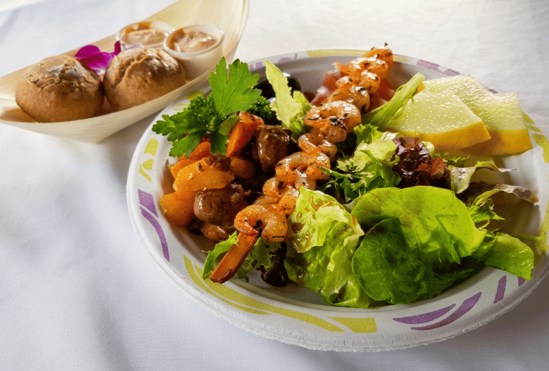 Garnelenspieß auf Fruchtsalat | Event Catering Uelzen Gegrillter Garnelenspieß auf einem fruchtigen Blattsalat-Bett, ein kulinarisches Highlight für Buffets und Business-Events in Uelzen.